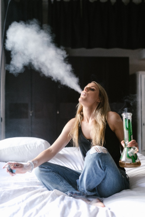 a woman using a bong on the bed